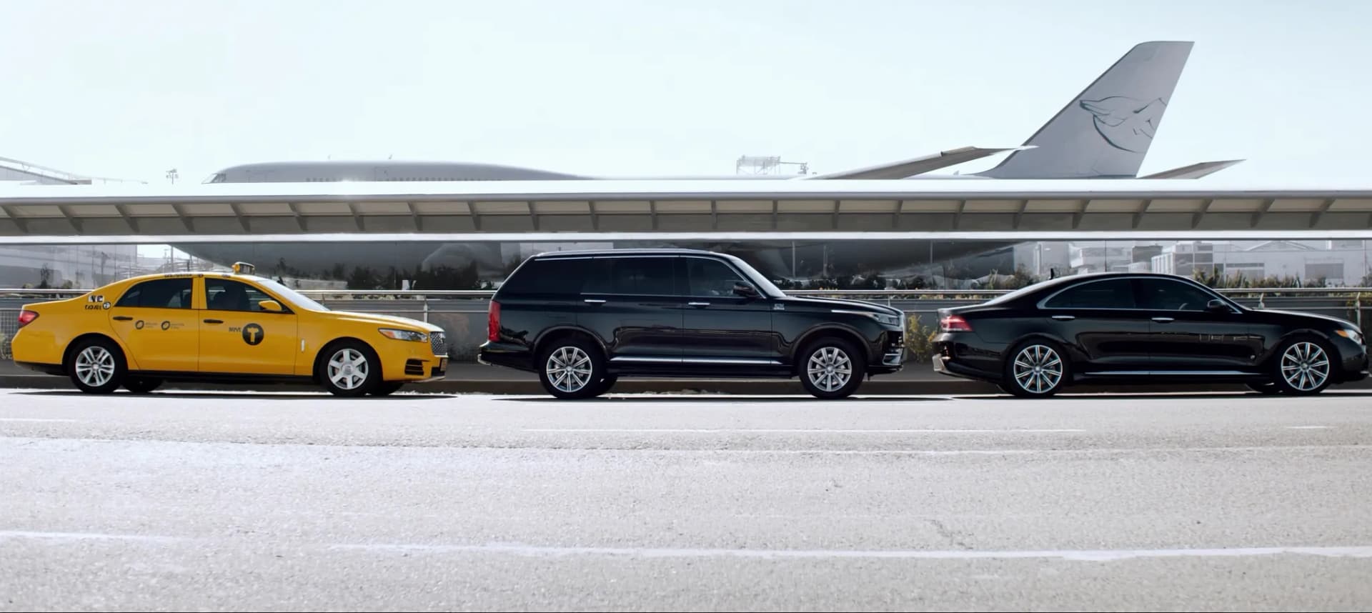 Chauffeur loading luggage into a black luxury sedan at JFK airport arrivals